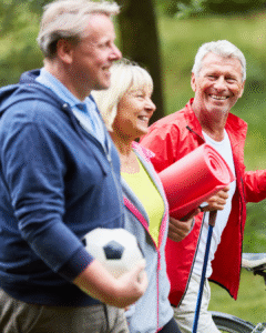 Starejši aktivni ljudje na sprehodu v naravi, nasmejani in polni energije – naravna podpora z dodatkom chlorelle za srce, možgane in vitalnost.